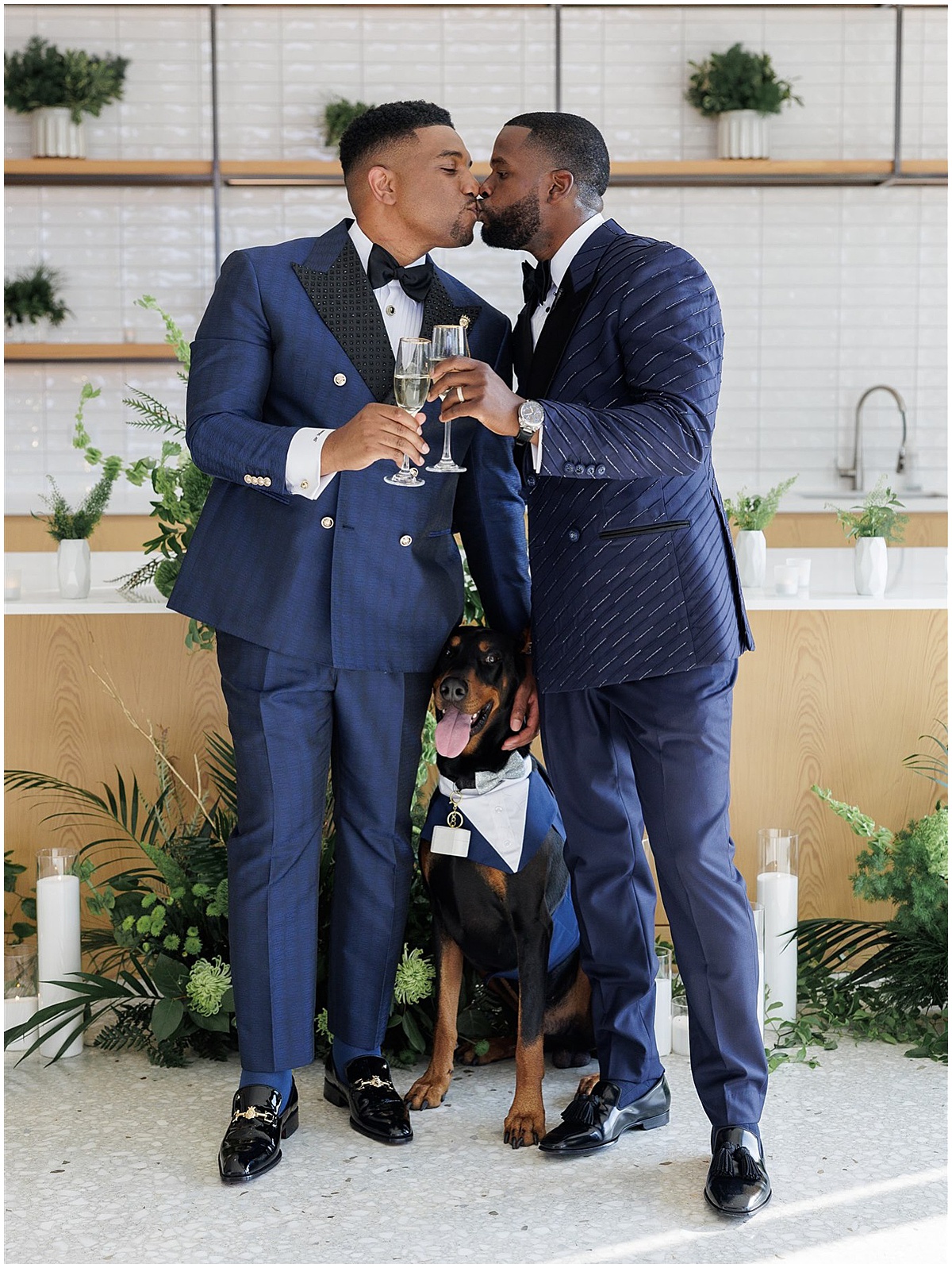 Two grooms kiss with their dog dressed in a tuxedo at their Palm Beach wedding
