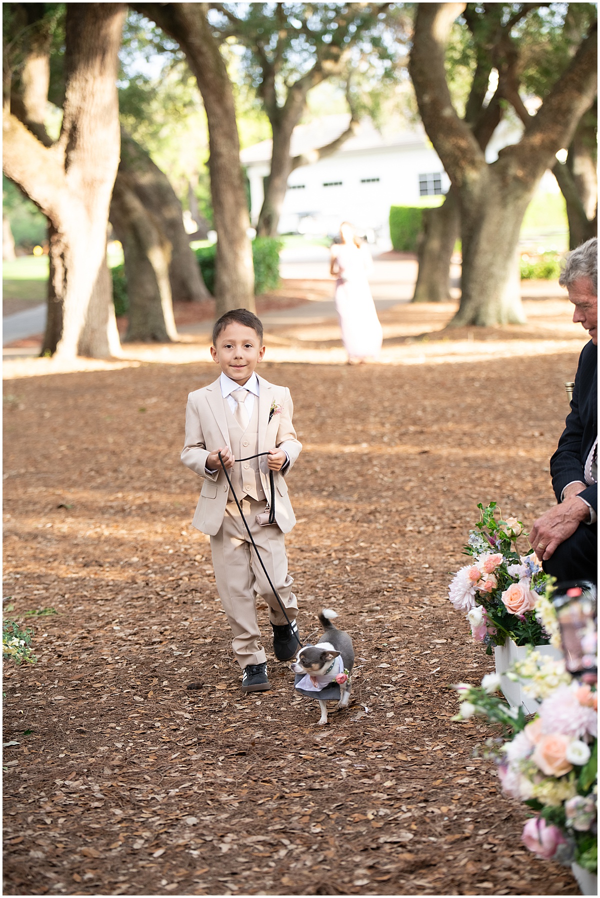 Dog walks down the aisle with a young ring bearer at an outdoor Palm Beach wedding